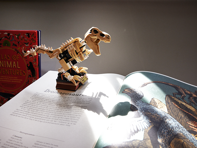 dinosaur-modell i lego står oppå en oppslått bok