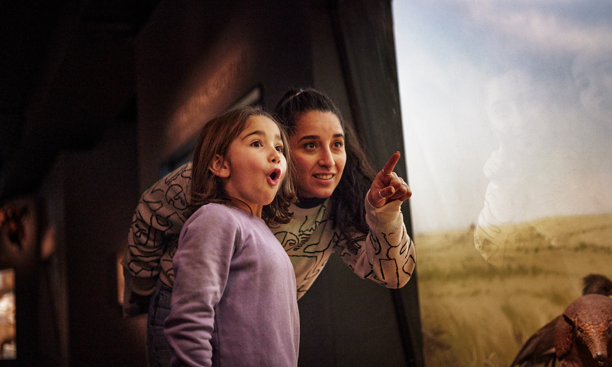 jente og kvinne viser med entusiastiske ansikter i zoologisk utstilling på museum