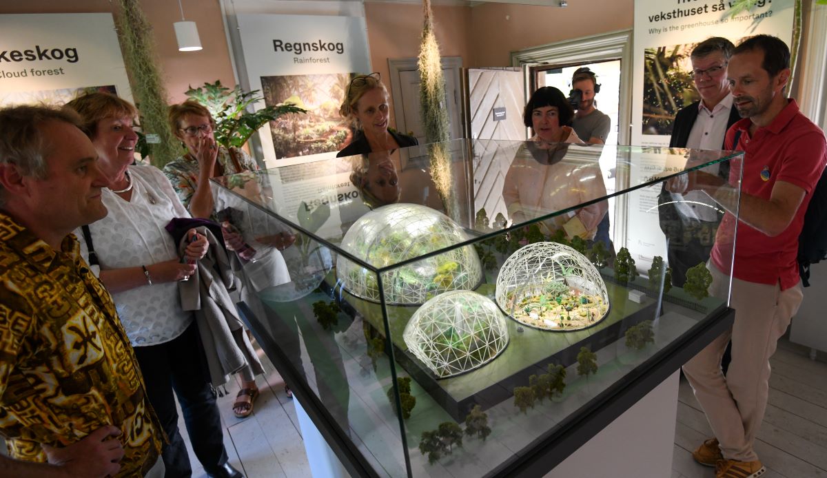 Begeistrede mennesker rundt modell av kupler med veksthusplanter