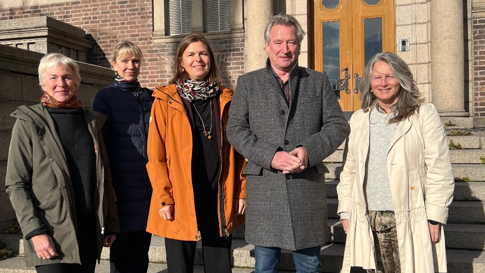 de fem direktørene står ute foran en bygning, foto