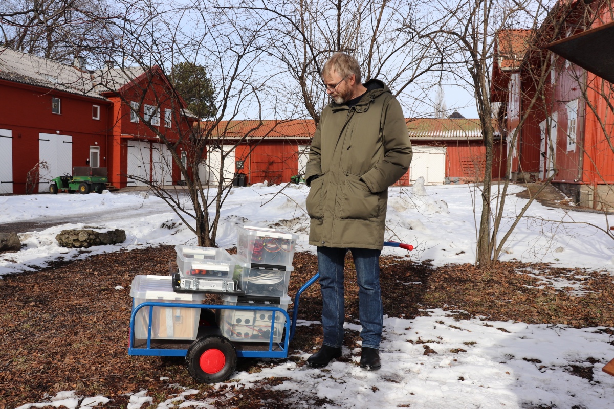 mann står og ser ned på en tralle med masse bokser med ledninger