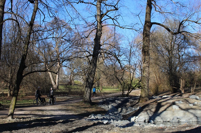 Bilde av parklandskap med trær og bekk.