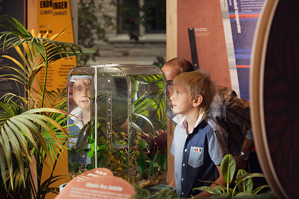 gutt og far ser på objekt i utstilling, et akvarie. refleksjon av gutten i akvarieglasset.